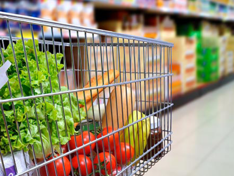 Ein mit Salat, Tomaten und Brot gefüllter Einkaufswagen in einem Supermarktgang