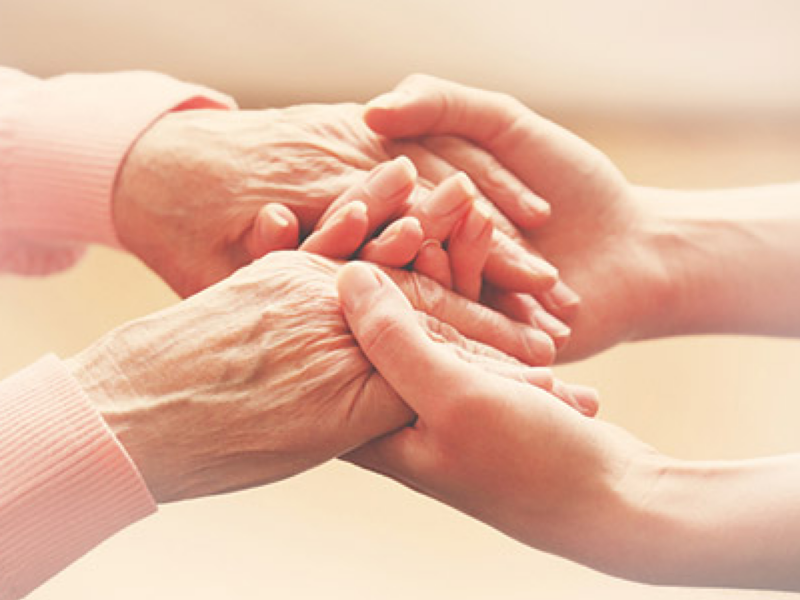 Eine Frau hält die Hände einer Seniorin fest