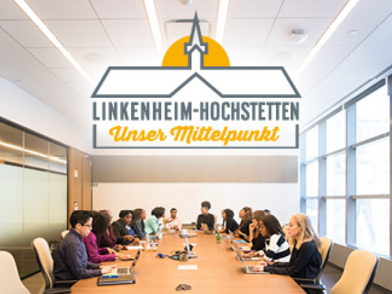 Personen, die an einem großen Konferenztisch sitzen und diskutieren, darüber ist das Logo von Linkenheim-Hochstetten gesetzt